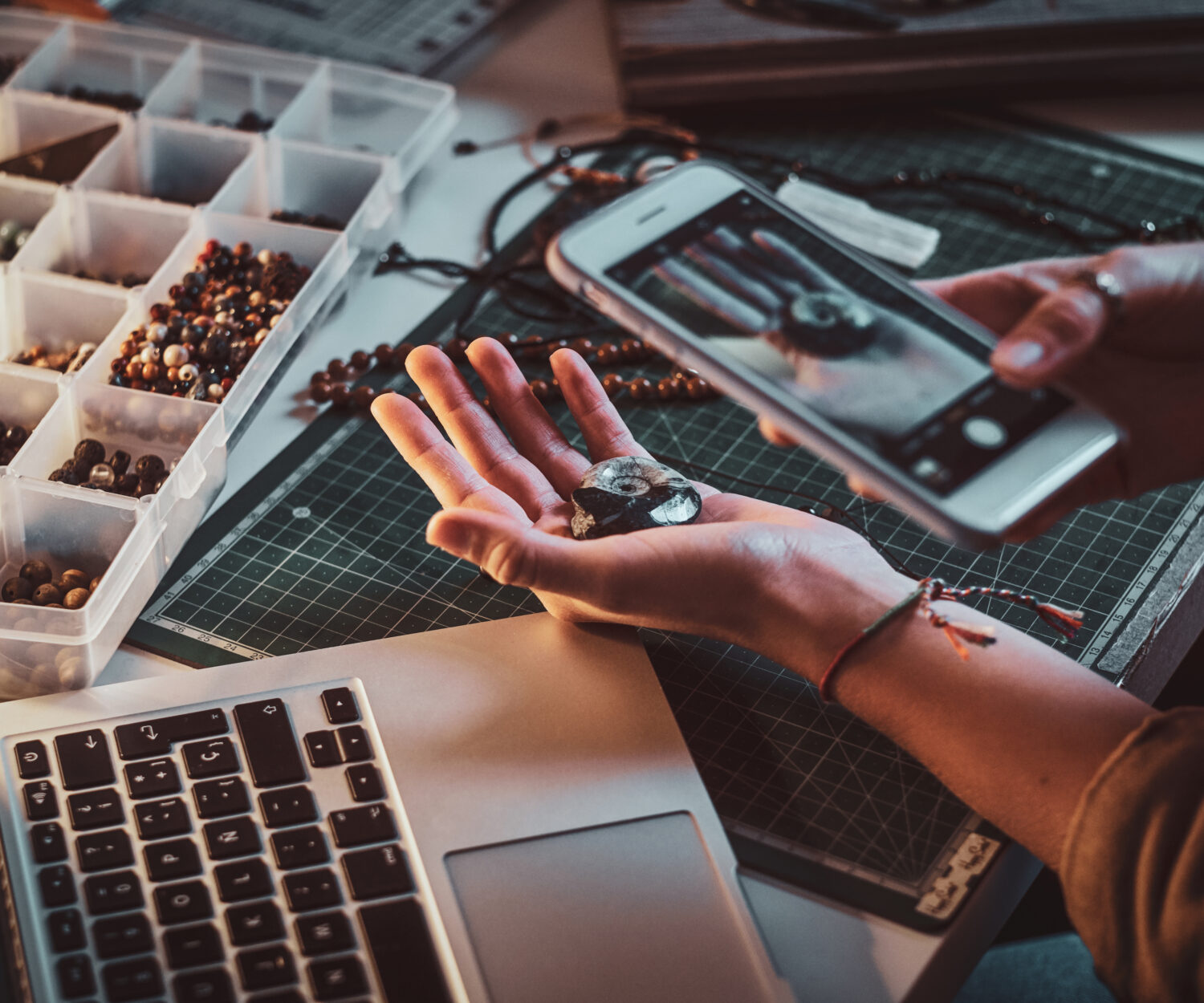 Creative student making photo of shell via smartphone while sitting at her workplace.